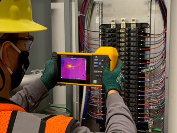 Electrician providing electrical maintenance at a client facility